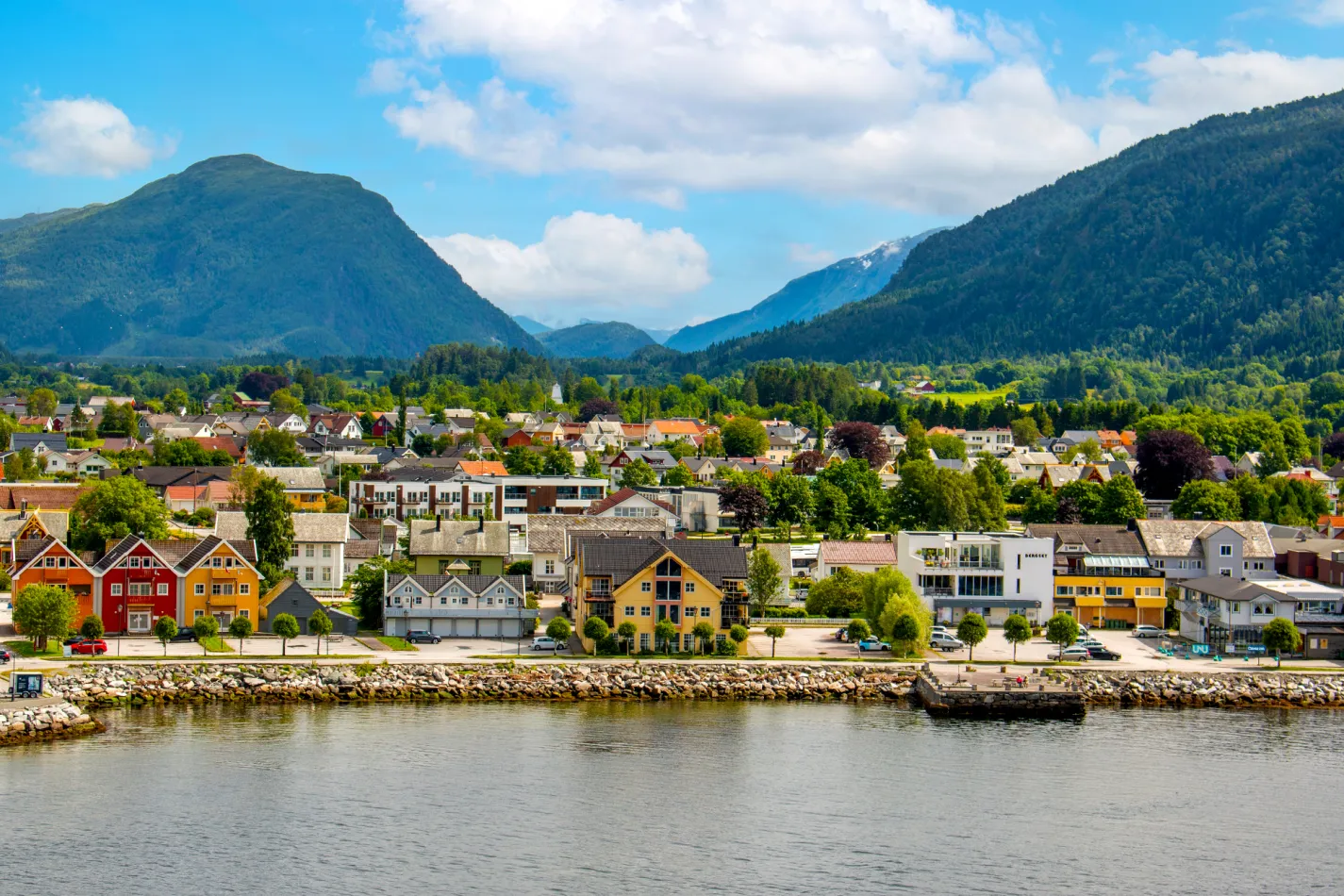 Colorful homes and businesses along the water's edge with tall mountains in the background