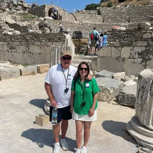 A smiling couple stand among ancient structural ruins