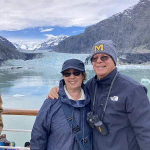 A smiling couple with the mountains and blue ocean behind them