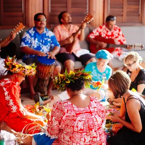 Group of travelers sitting together listening to Hawaiian musicians playing instruments