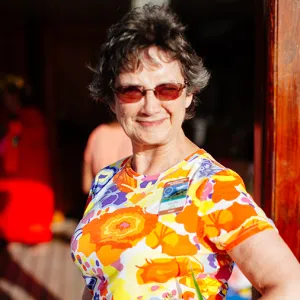 Smiling woman wearing sunglasses and a colorful shirt with orange flowers on it